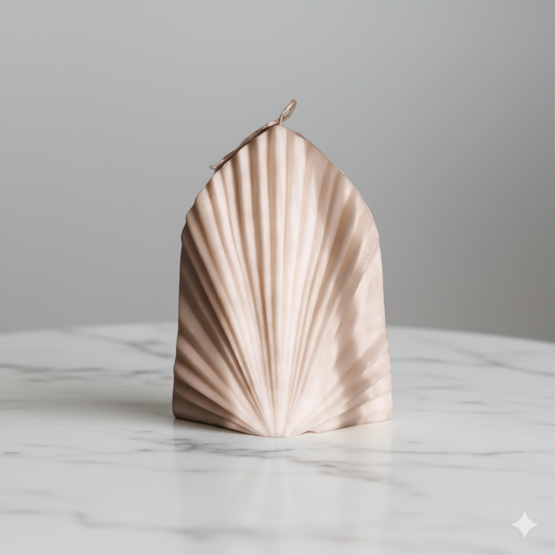 Shell-shaped candle on a marble surface with a grey background. Great gift idea