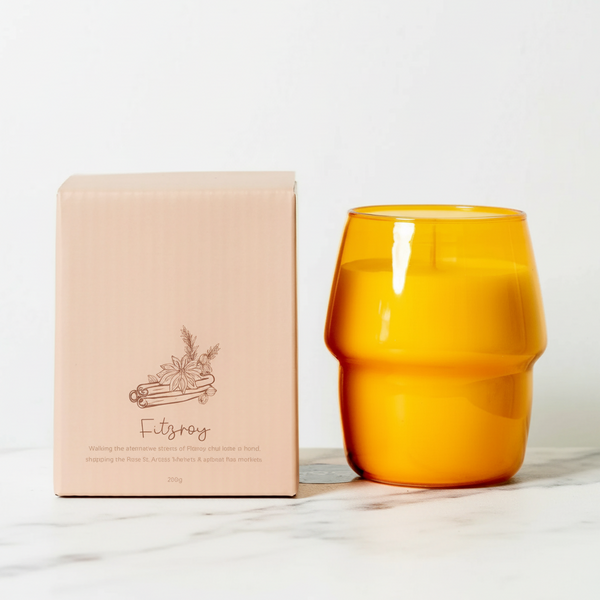 Orange glass candle and pink box on a white background