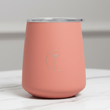 Coral-colored tumbler with a silver lid on a white marble surface. 