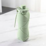 Collapsible green water bottle on a white surface